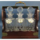 An Edwardian style mahogany tantalus with three decanters with Coalport china labels, Whisky, Gin
