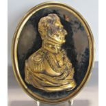 A gilt bronze profile relief of The Duke of Wellington set on a black velvet mount in a brass oval