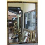 An antique wall mirror, the rectangular ebonised frame with decorative applied foliate and bead