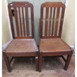 Pair of old English oak rail back dining chairs with solid seats, with carved detail incorporating