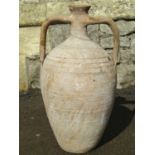 An old buff coloured terracotta amphora with drawn bottleneck, moulded open loop handles and