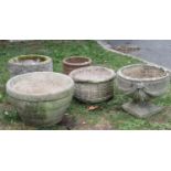 Four weathered cast composition stone circular garden planters of varying design, one in the form of