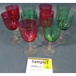 Twenty five cranberry red baluster wine glasses on slender stems, and eight green baluster wine