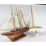 A wooden model of a three masted yacht, 64 cm raised on a wooden stand and a wooden pond yacht.