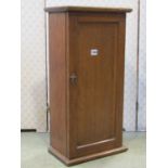 A late Victorian oak hanging wall cupboard, enclosed by a rectangular panelled door, with shelved