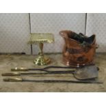 A polished copper helmet shaped coal bucket, a brass kettle stand with pierced detail, and a set