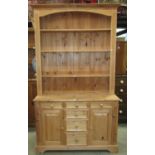 A stripped pine kitchen dresser, the base enclosed by a pair of rectangular fielded panelled