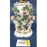 A 19th century continental porcelain oil lamp frame, the oviform font supported by two cherubs, with