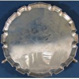 A small silver tray with shaped edge, raised on three pad feet, London 1930, maker Ernest J Lowe,