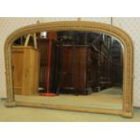 A Victorian overmantel mirror with arched and moulded gilt frame, with repeating floral and bead