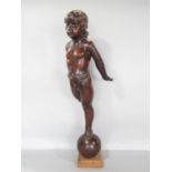 A carved mahogany cherubic figure balancing on a sphere, ( The right leg is present to be