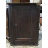 A Georgian oak countrymade hanging comer cupboard enclosed by a rectangular panelled door over three