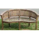 A stained hardwood banana shaped garden bench 160 cm wide