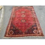 A large Middle Eastern carpet with three central medallions on a field of stylised flowers on a