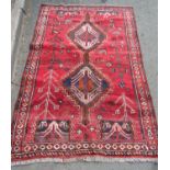 A Persian rug with stylised birds and flowers and an interlocking medallion on a red ground, 164cm