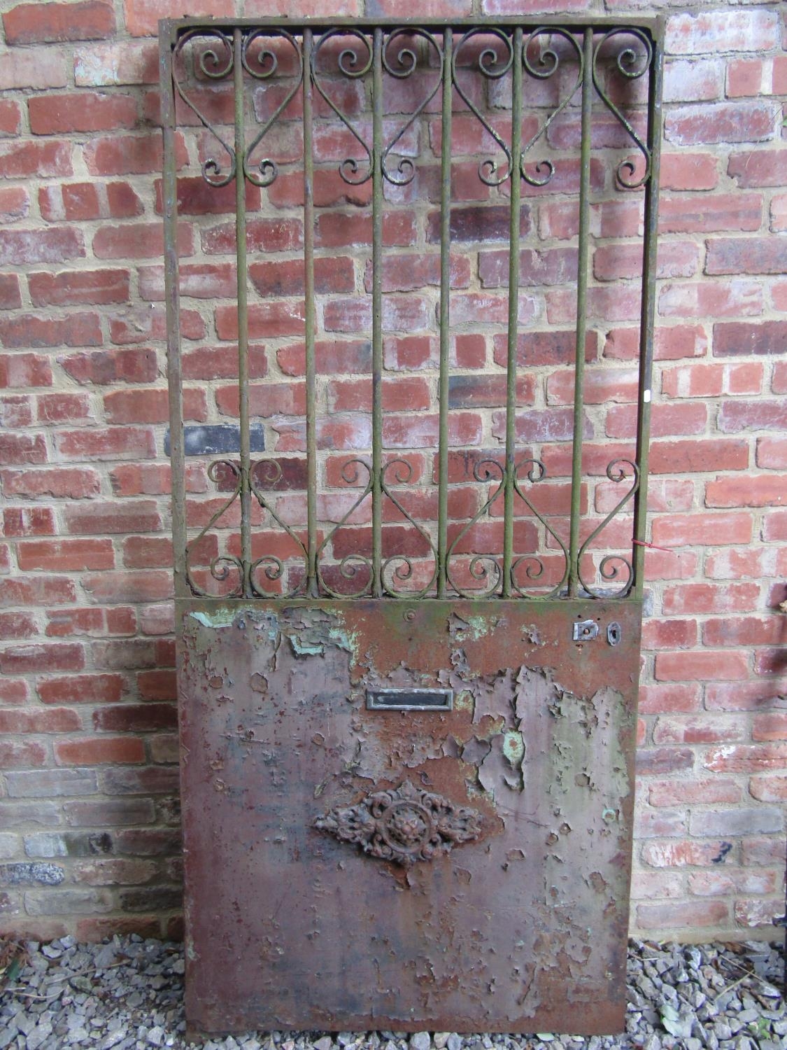 A heavy gauge ironwork door/security gate with simple open scrollwork detail, approximately 100 cm