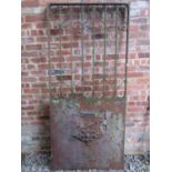 A heavy gauge ironwork door/security gate with simple open scrollwork detail, approximately 100 cm