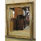 A large contemporary antique style wall mirror with bevelled edge plate within a swept and moulded