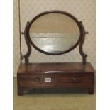 A small 19th century mahogany toilet mirror with oval plate, raised on shaped and scrolled supports,