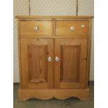 A small stripped pine side cupboard, freestanding and enclosed by a pair of rectangular moulded