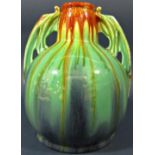An art deco style pottery vase of low form with drawn neck, drip glazed finish in blue, green