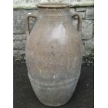 An old buff coloured terracotta jar with moulded loop handles 55 cm high