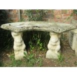 A small weathered cast composition stone three sectional garden bench with crescent shaped slab seat