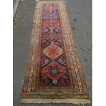 An Kazak design runner with a row of six gul to the centre 300cm x 95cm approx