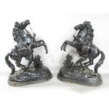 A pair of black painted spelter Marley Horse groups raised on a wooden base 42cm high x 33cm