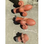 A pair of reclaimed terracotta faceted plume terracotta ridge finials together with one other (
