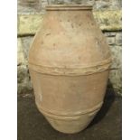 An old terracotta olive jar oviform with thumb pressed ring bands, 68 cm high