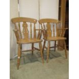 A pair of modern Windsor beechwood pierced fiddle back kitchen elbow chairs together with a pair
