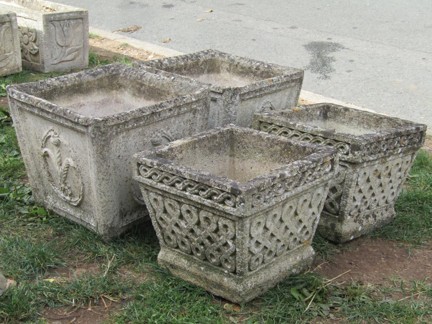 A pair of weathered cast composition stone planters of square tapered form with repeating fleur-de-