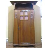 An arts and crafts oak hall robe of tapering form enclosed by a central door with quarter panelled