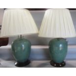 A pair of green crackle glazed table lamps on wooden stands and with silk pleated shades, 66cm high.