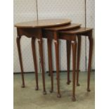A nest of three graduated walnut occasional tables, the outer table of oval form with well matched