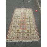 A Kazak corridor rug with several rows of medallions in faded tones of brown and yellow, 210cm x