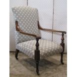 An antique low deep seated open armchair with shaped dished and scrolled arms raised on turned