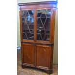 A Georgian oak freestanding corner cupboard, the lower section enclosed by a pair of panelled doors,