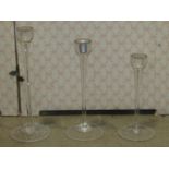 Twenty-nine contemporary tall stemmed glass candle holders of the same design but varying in height,