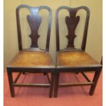 A pair of Georgian country made side chairs in oak with vase shaped splats, solid seats and square
