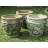 A set of three weathered cast composition stone garden planters of circular tapered form with