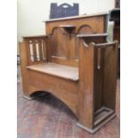 An arts and crafts oak hall bench with box seat, panelled back and pierced sides supporting two open