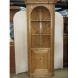 A stripped pine floorstanding corner cupboard in the Georgian style, partially enclosed by