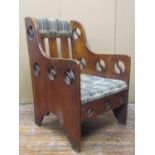 An arts and crafts elbow chair, with upholstered seats and back panel, the framework with pierced