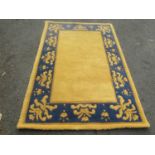 A thick pile wool carpet with a yellow rectangular panel and a yellow and blue border, 180cm c 120cm