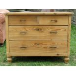 A stripped pine bedroom chest of two long and two short drawers with bar handles, flanked by rounded