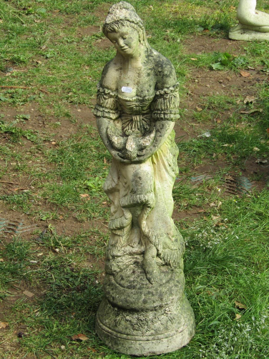 A weathered cast composition stone garden ornament in the form of a standing maiden releasing a