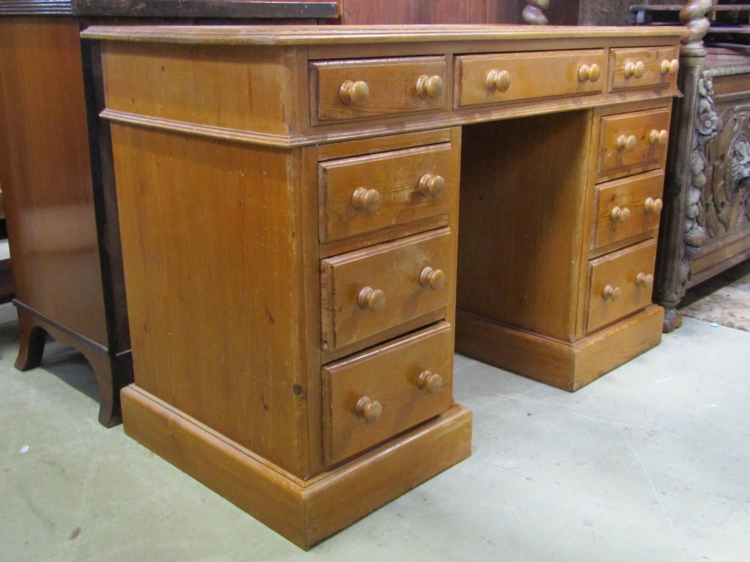 A stripped pine kneehole twin pedestal desk fitted with nine drawers set on moulded plinths, 118cm