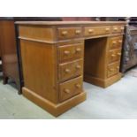 A stripped pine kneehole twin pedestal desk fitted with nine drawers set on moulded plinths, 118cm